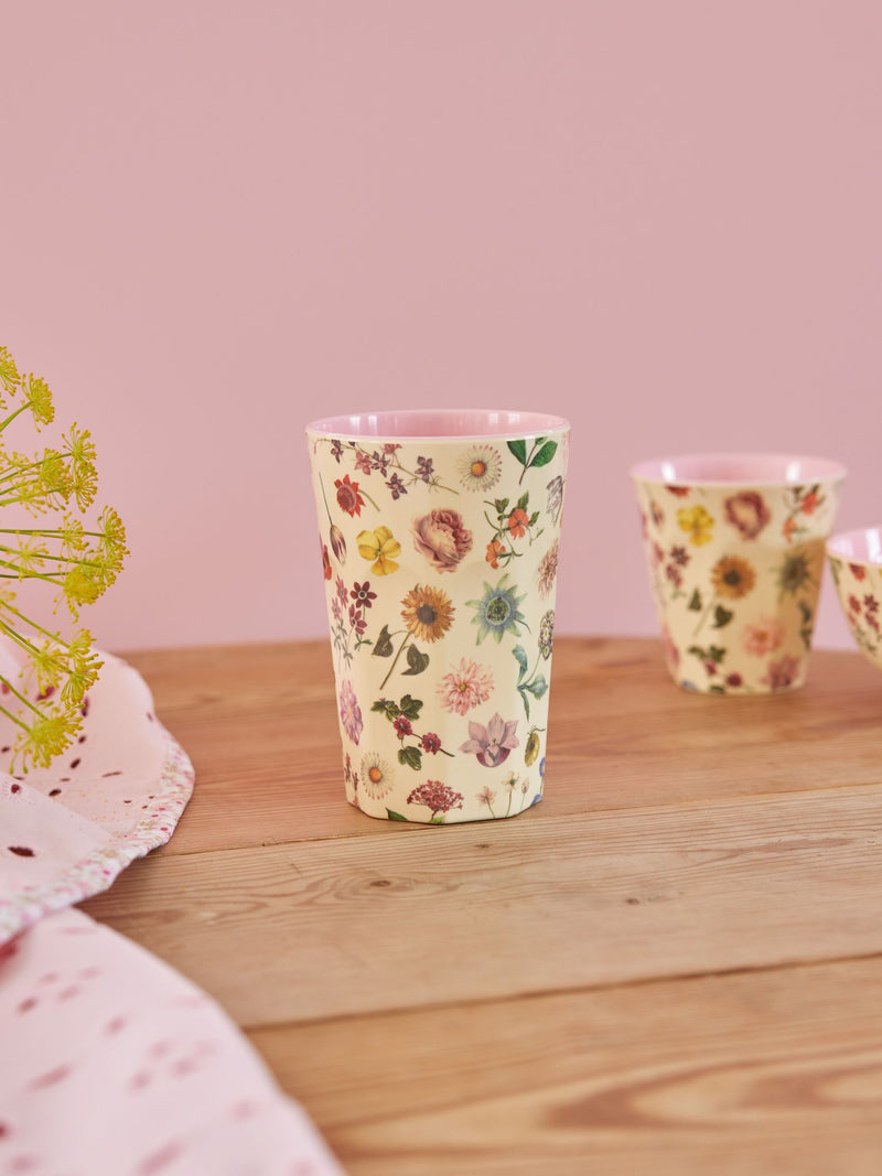 Wooden table with matching table cloth and a tall cream cup.